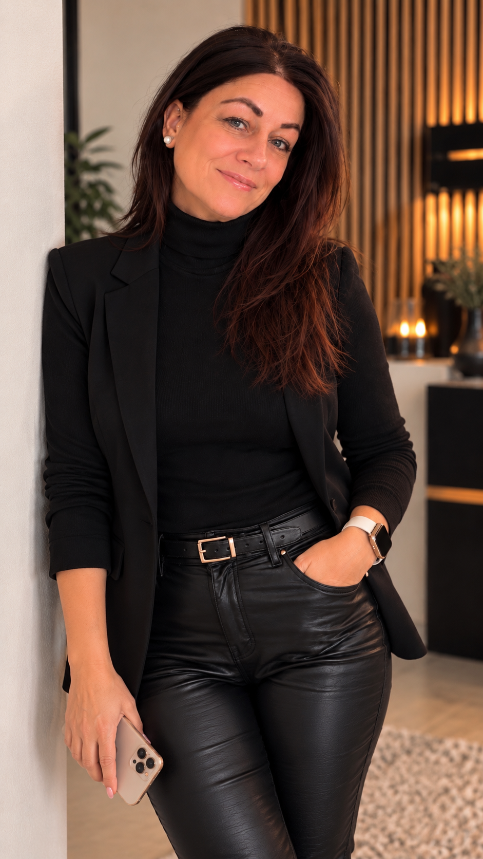 Petra Osterode im schwarzen Blazer und Lederhose an einer hellen Wand.
